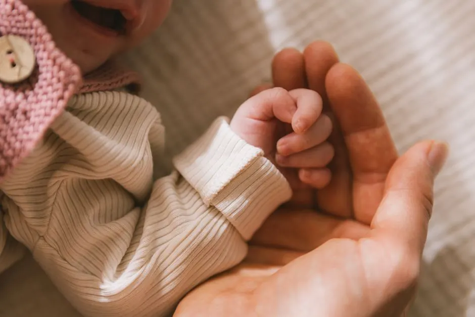 Tender close-up of a parent gently holding a newborn baby's hand, symbolizing care and love.
